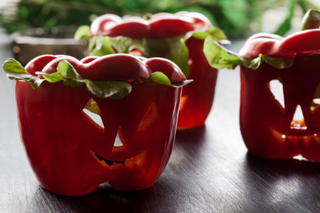 Halloween food. Red sweet bell peppers with cut out facesの写真素材