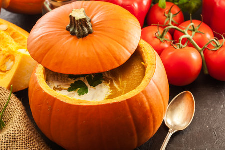 Pumpkin soup with cream in a pumpkin for autumn dinnerの写真素材