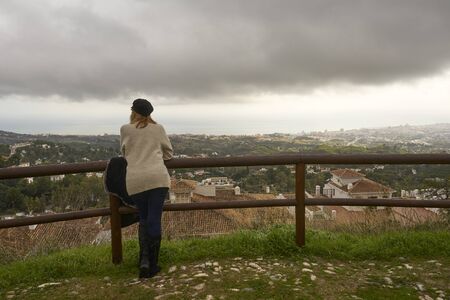 blonde woman on her back looking at the horizon on a cloudy dayの写真素材