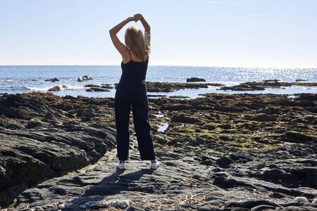 blonde girl watching the sea with sky and blue sea