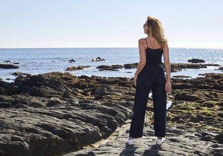 blonde girl watching the sea with sky and blue sea