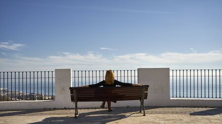 pretty woman contemplating the sea with a blue sky and white clouds