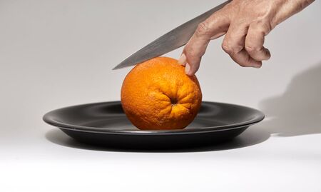 still life of a woman hand cutting an oranges on white backgroundの写真素材