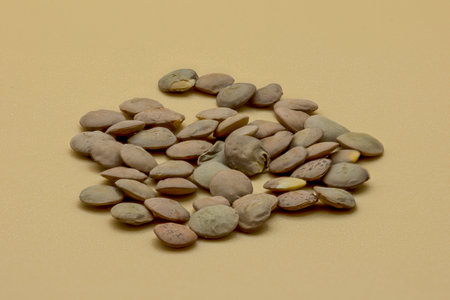 Green lentils in a top view with an orange background.