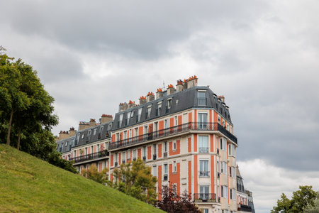 Traditional Parisian buildings with wrought iron balconies and mansard roofs are standing on a hill...