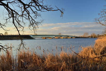 Bridge over a wide river and lagoon at sunrise, picturesque clouds in the sky. Spring.の写真素材
