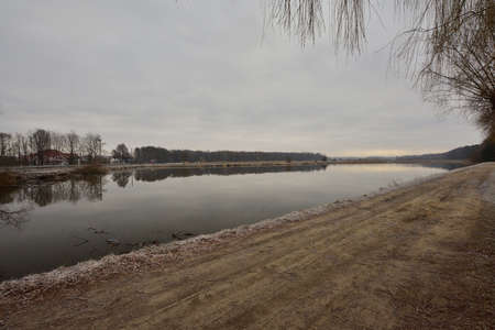 The causeway separates the bank of the pond from the river on a gloomy morning on an autumn cold...