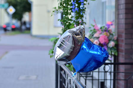 A silver and blue balloon tied to a metal railing against the background of traffic. Bokeh.の写真素材