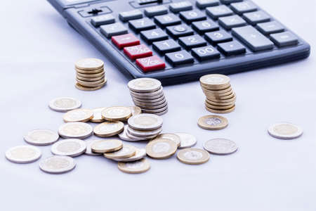 Coins and calculator on an isolated white background.の写真素材