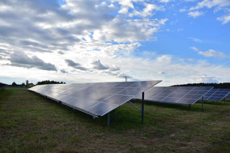 Ground-mounted solar panels generate electricity on a cloudy day. Clouds.