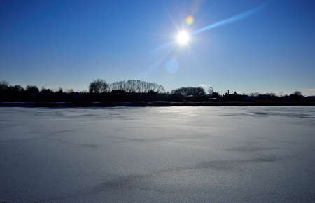 Winter sun on a frozen lake covered with snow on a frosty winter day. Winter.の写真素材