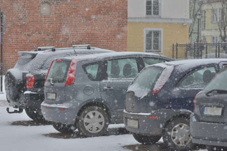 Snow-covered road, wheel marks in the snow and snow-covered cars during heavy snowfall. Day.の写真素材