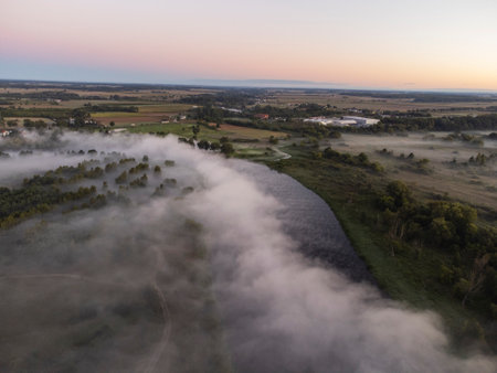 Pictures of the drone flight over the fog. River, forest, fields and meadows on a misty summer dawn.の写真素材