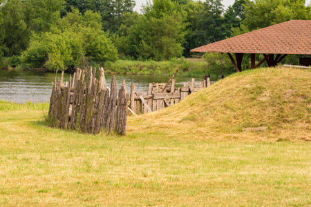 Stockade and shed on a green meadow against the background of a river and forest on a sunny day. Summer.の写真素材