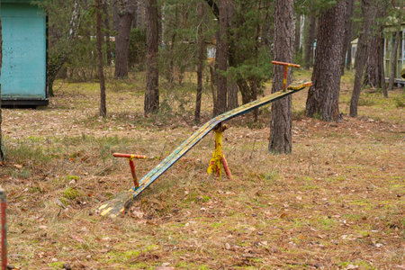 An old, dilapidated children's swing in an abandoned and forgotten holiday resort in the forest. Urbex.の写真素材