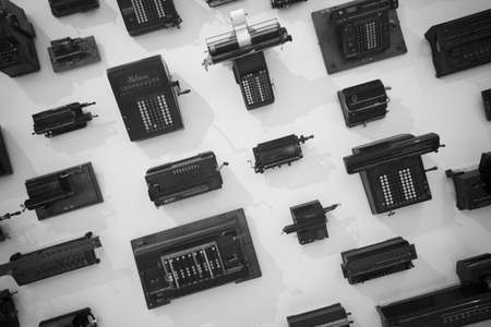 many antique calculators hanging on a white wall, showing history of calculation and computersの写真素材