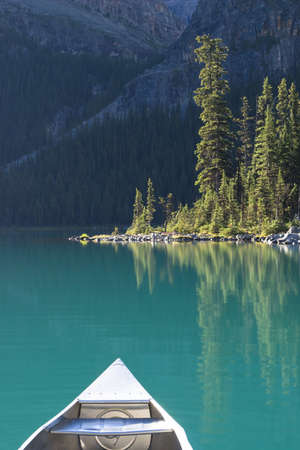 front part of a canoe on lake ohara with trees and mountain in backgroundの写真素材
