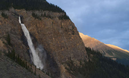 takkakaw falls with mountain tops glowing orange in sunset light, canadian rockies,british columbiaの写真素材