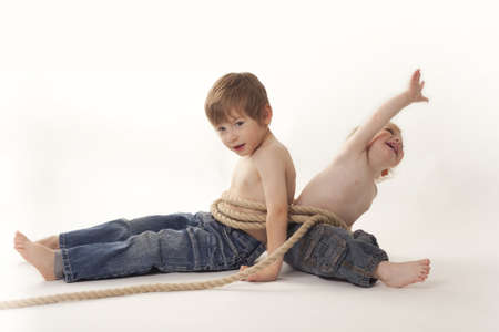 two boys tight together with rope,sitting on floor,white backgroundの写真素材