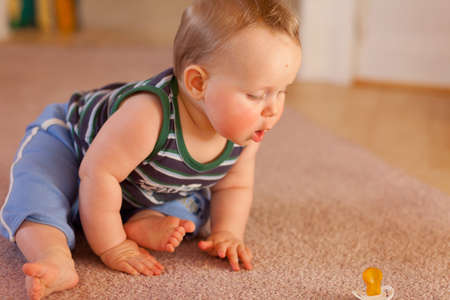 baby determined to reach pacifier,boy,7 months old on carpet