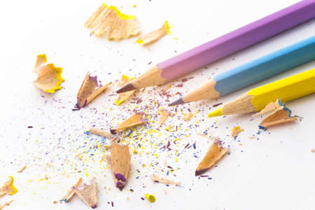 cyan magenta yellow pencils with splinter waste on white paper