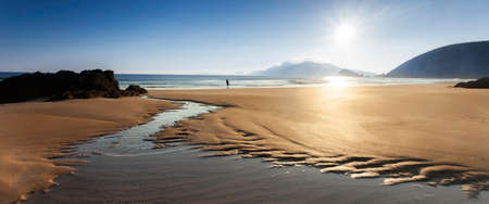 Tidal creek with ocean and single man looking out,  location  Coumenoole Beach pointing towards Lure  most western mainland point of Europe , county kerry, western Irelandの写真素材