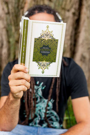 Man reading in Koran, hidden behind book, Germanyの写真素材