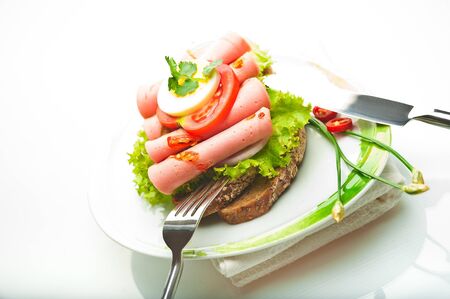 Brown bread with chili sausage slices green salad tomato and eggの写真素材