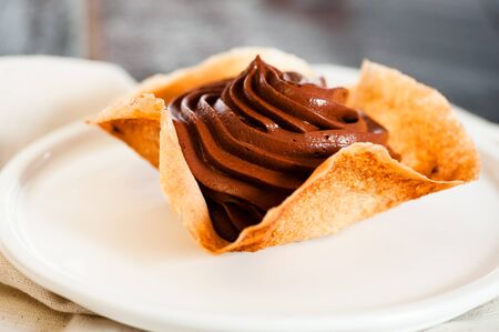 Mousse au chocolat in a tuile basket on dark old wooden table