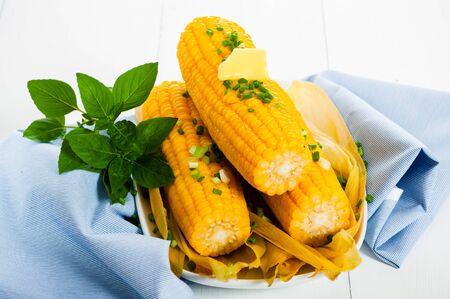 Cooked corn with butter and chives on white backgroundの写真素材