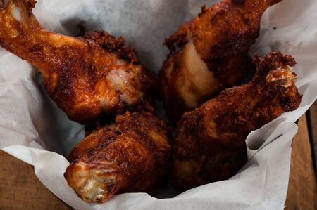 Four chicken drumsticks in a bowl on a wooden tableの写真素材