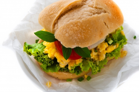 Fresh bun with vegetables and scrambled egg on white background