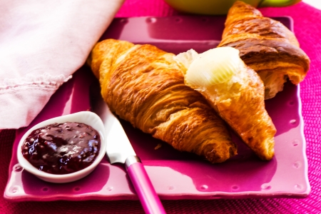 fresh breakfast - jam and croissant on a pink plate