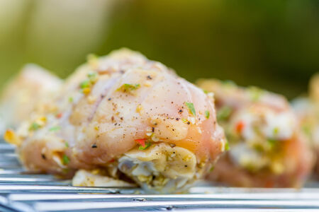 Closeup of Raw chicken drumsticks on a barbecue grill, outdoors in the gardenの写真素材
