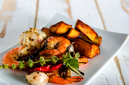 fresh shrimps served on a white plate with garlic onion chili and fried potatoesの写真素材