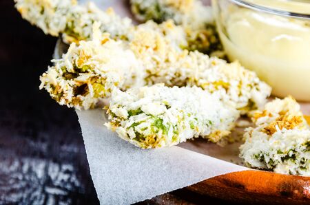 breaded baked avocado pieces served with a mayonnaise sauce on clay plate and wood backgroundの写真素材