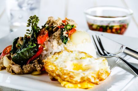 Thai spicy food basil pork fried with rice and fried egg and chili fish sauce,Pad Kra Pao mooの写真素材