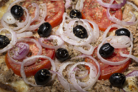 pizza with onions, tuna, tomatoes and olives on wooden tableの写真素材