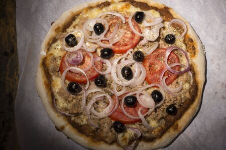 pizza with onions, tuna, tomatoes and olives on wooden tableの写真素材