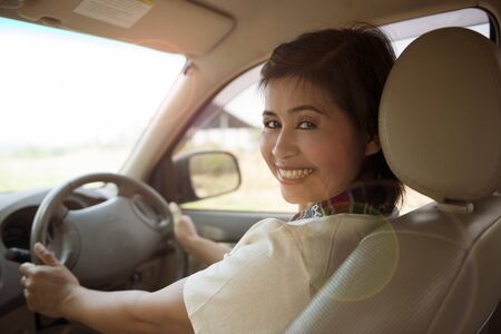 Smiling woman that drive a car is looking behindの写真素材