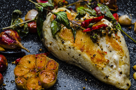 fresh fried chicken breast in a pan with garlic chili and some wild bailicumの写真素材