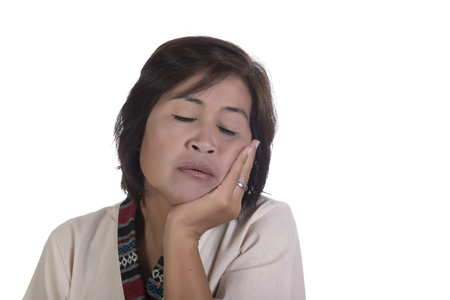 Single exhausted mature woman with tired expression, eyes closed and chin in palm over white backgroundの写真素材