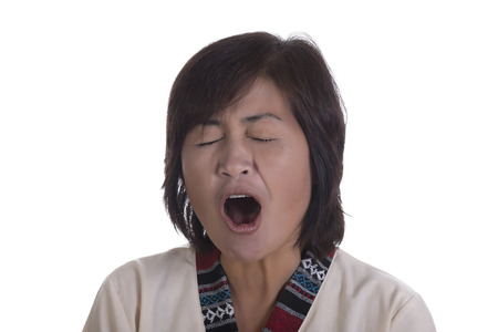 Single tired female adult yawning with mouth wide open and both eyes shut over white backgroundの写真素材