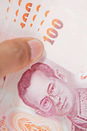 Male hand holding Thai money banknotes