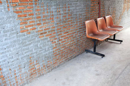 Orange chair standing in room over orange brick wallの写真素材