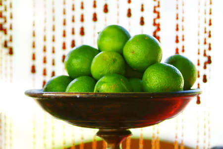 a brown fruit dish with green limes insideの写真素材