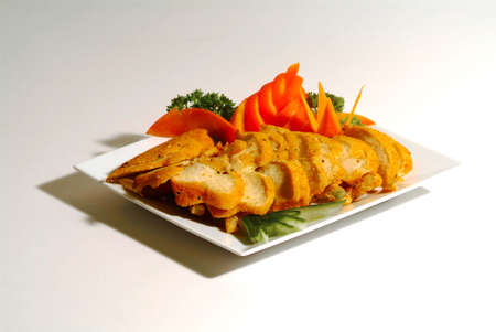 decorated variegated roast chicken on white plate of white backgroundの写真素材