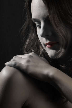 a young woman holds her hand on her shoulderの写真素材