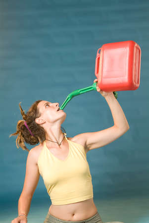 a young woman drinks from a red petrol canの写真素材