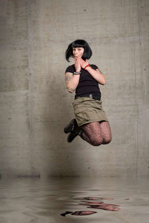 a young woman junping in front of concrete background